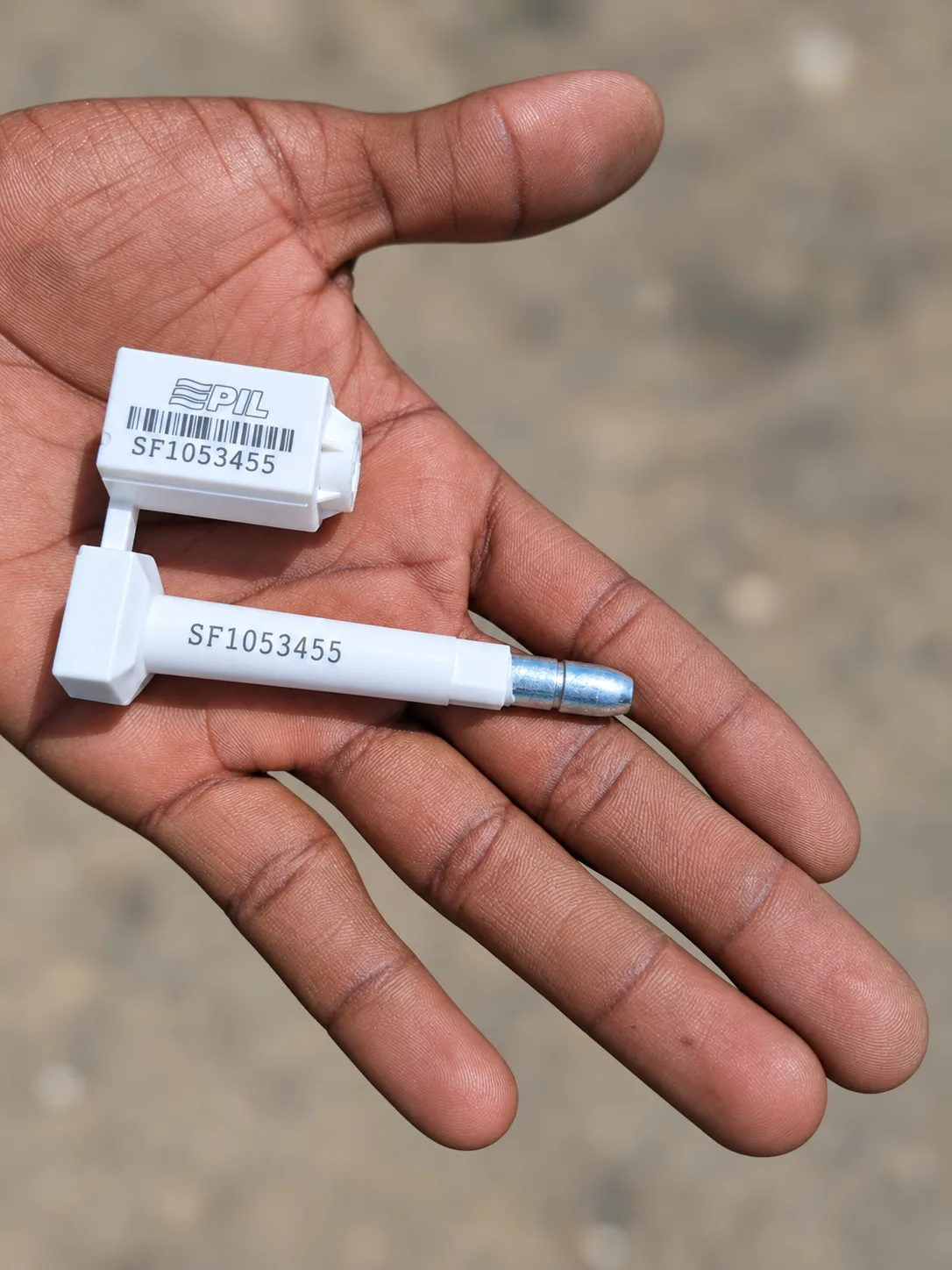 A white numbered container bolt seal held in a hand